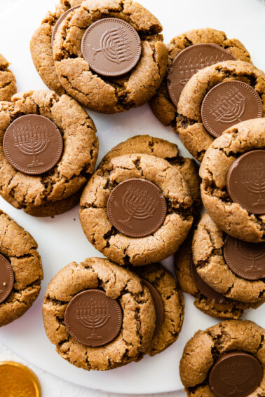 Multiple peanut butter blossoms with a chocolate coin that depicts a menorah in the center of each cookie.