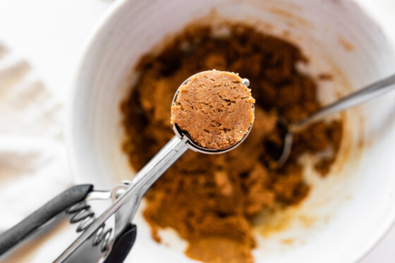 A small cookie scoop holding a portion of the batter that will be used to make peanut butter blossoms.