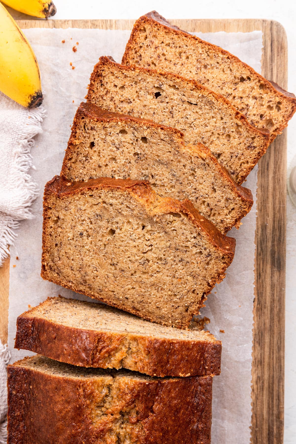 Four slices of banana bread leaning against one another on a wooden board.