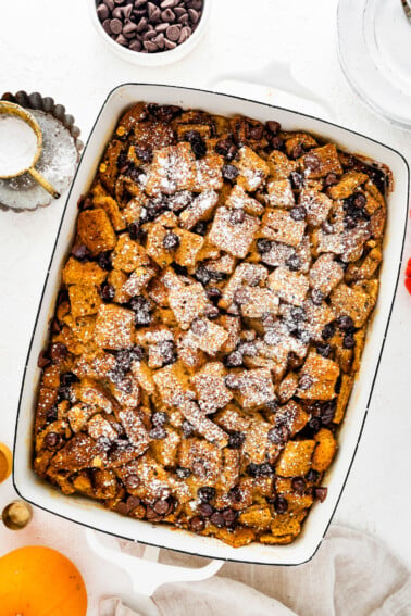 Pumpkin French Toast Casserole in a square baking dish topped with powdered sugar and chocolate chips.