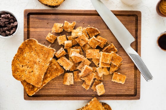 Toast cut into squares on a wooden cutting board.