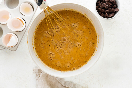 almond milk, pumpkin, maple syrup, eggs, vanilla and pumpkin pie spice in a large mixing bowl with a metal whisk.