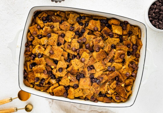 Toast cut into squares in a large square baking dish and topped with chocolate chips.