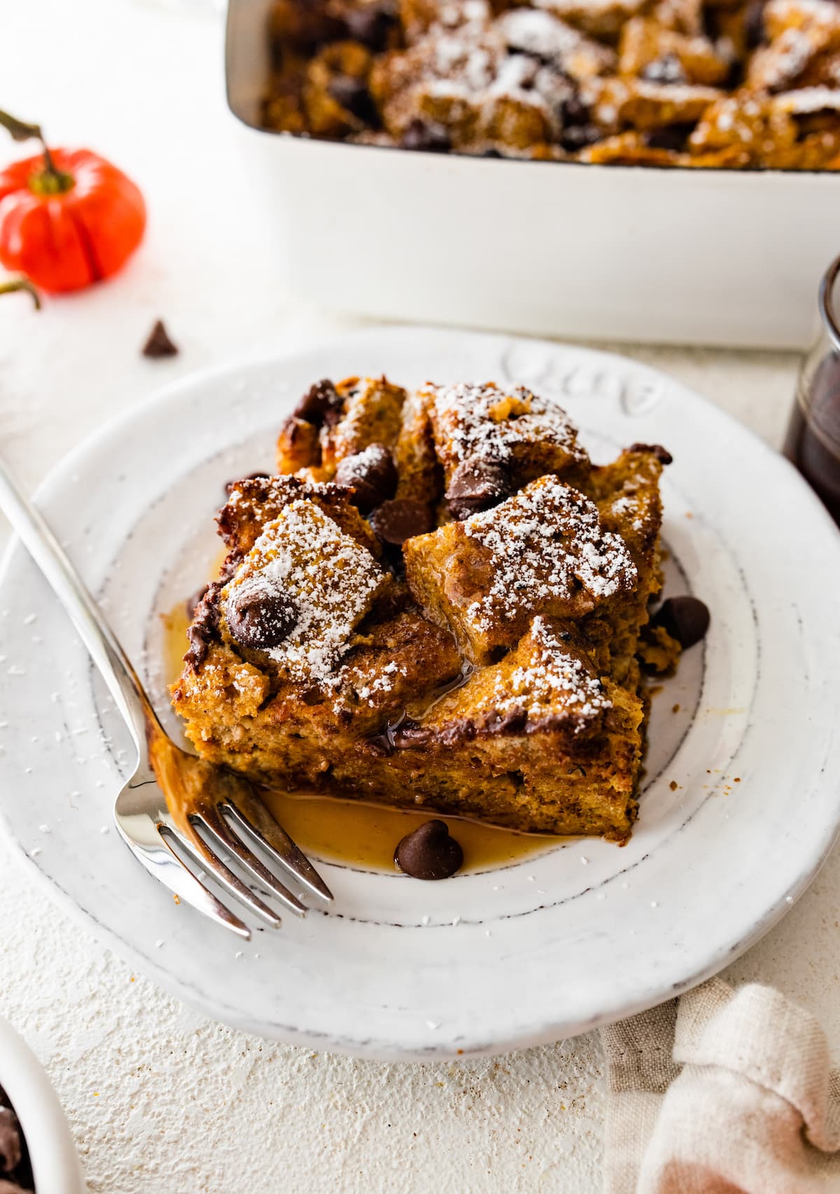 A serving of Pumpkin French Toast Casserole on a small plate with maple syrup.
