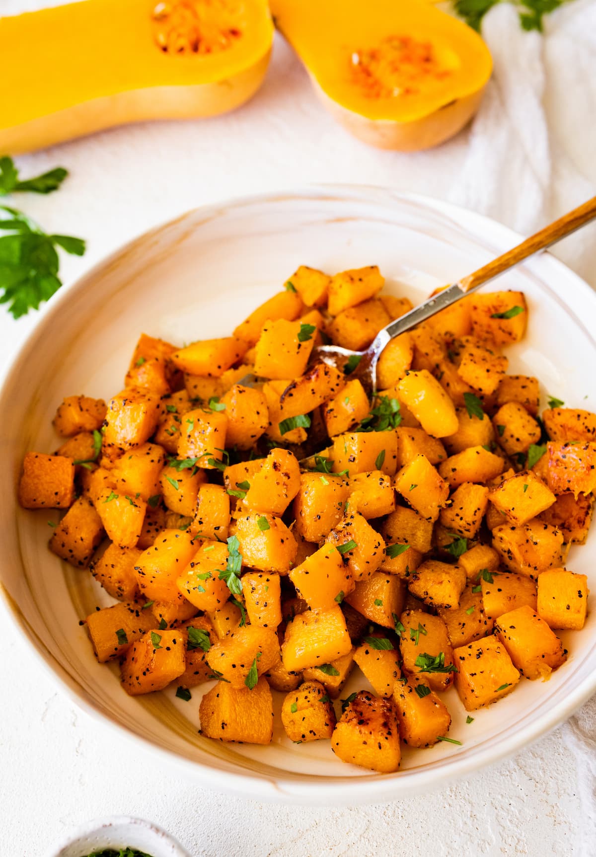 Seasoned and roasted butternut squash cut into cubes in a bowl.