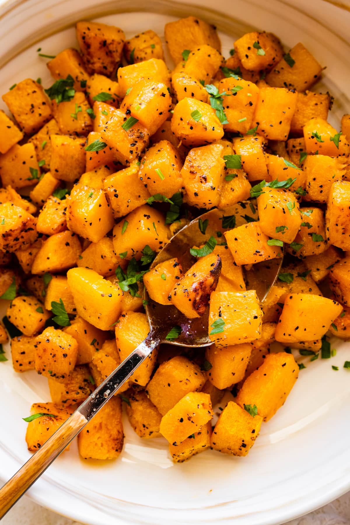 Seasoned and roasted butternut squash cut into cubes in a bowl.