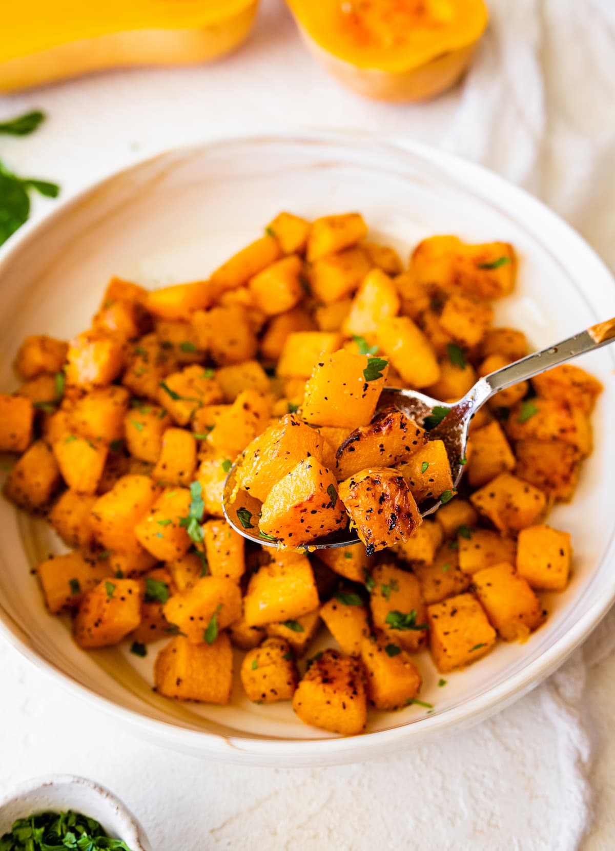 Roasted butternut squash on a spoon over a large bowl of the squash.