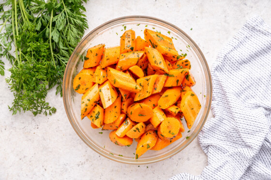 Cut carrots with fresh herbs in a large glass bowl.