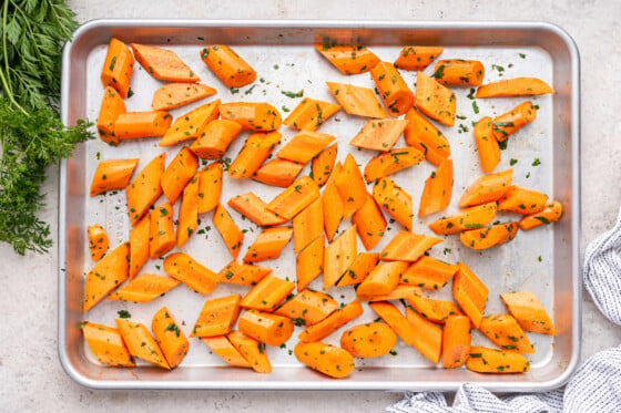 Cut carrots with fresh herbs on a baking tray.
