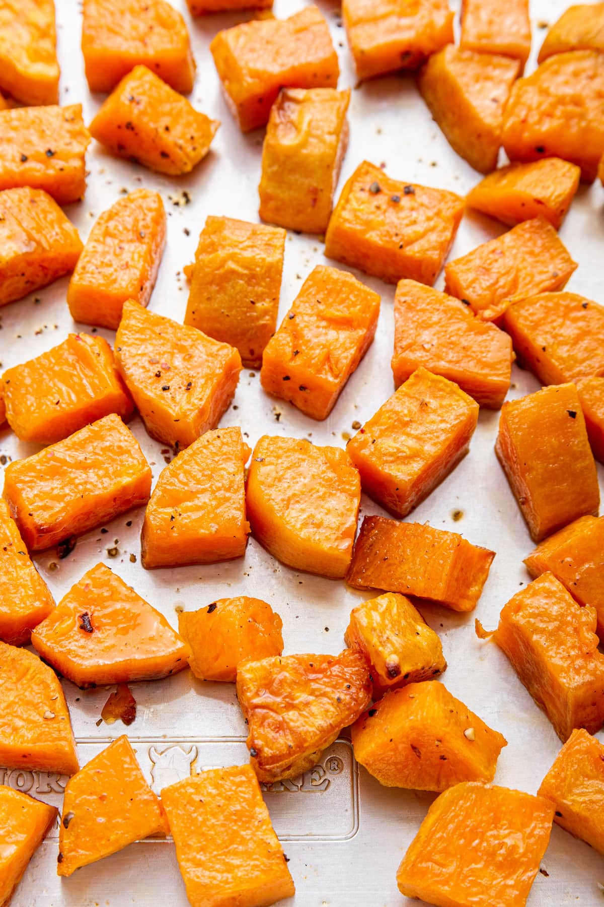 Cubed roasted sweet potatoes on a baking tray.