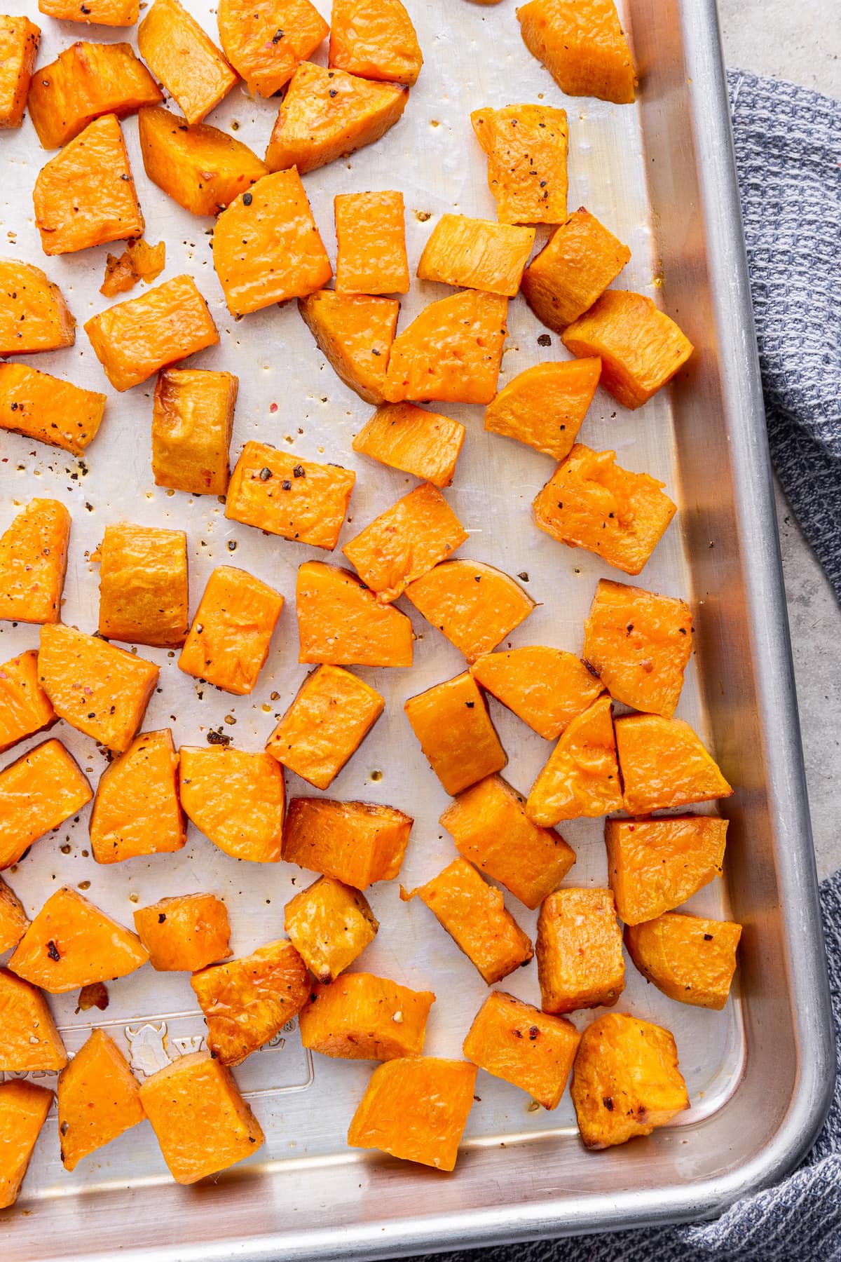 Cubed roasted sweet potatoes on a baking tray.