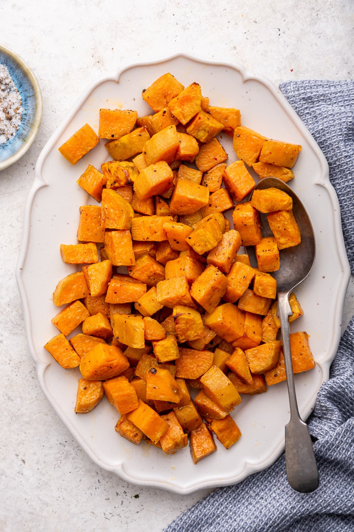 Cubed roasted sweet potatoes on a plate with a metal spoon.