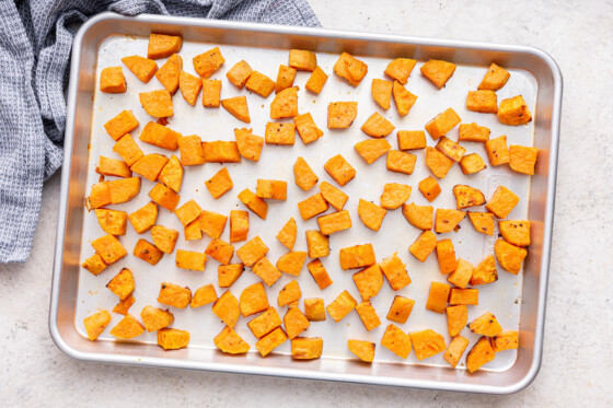 Cubed and roasted sweet potatoes on a baking tray.