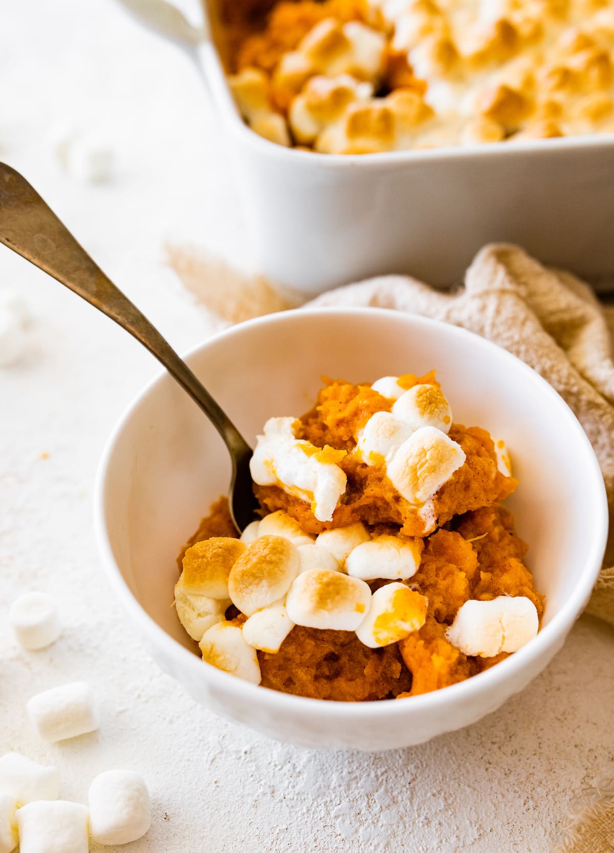 A serving of sweet potato casserole in a small bowl with a metal spoon.