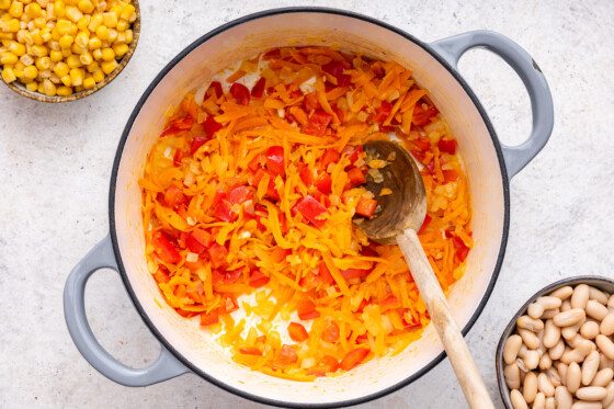 Grated carrots, pepper, onion and garlic in a large pot with a wooden spoon.