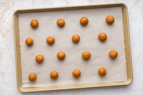 Peanut butter cookie dough balls formed on a baking sheet.