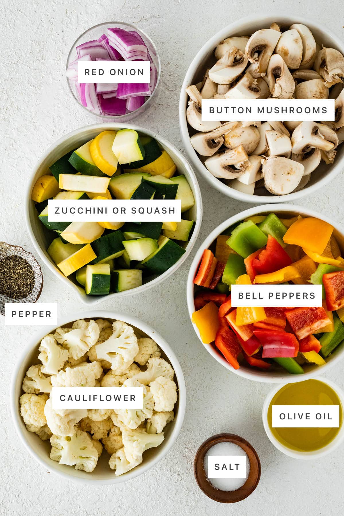 Ingredients measured out to make Air Fryer Vegetables: red onion, button mushrooms, zucchini, squash, pepper, bell peppers, cauliflower and salt.