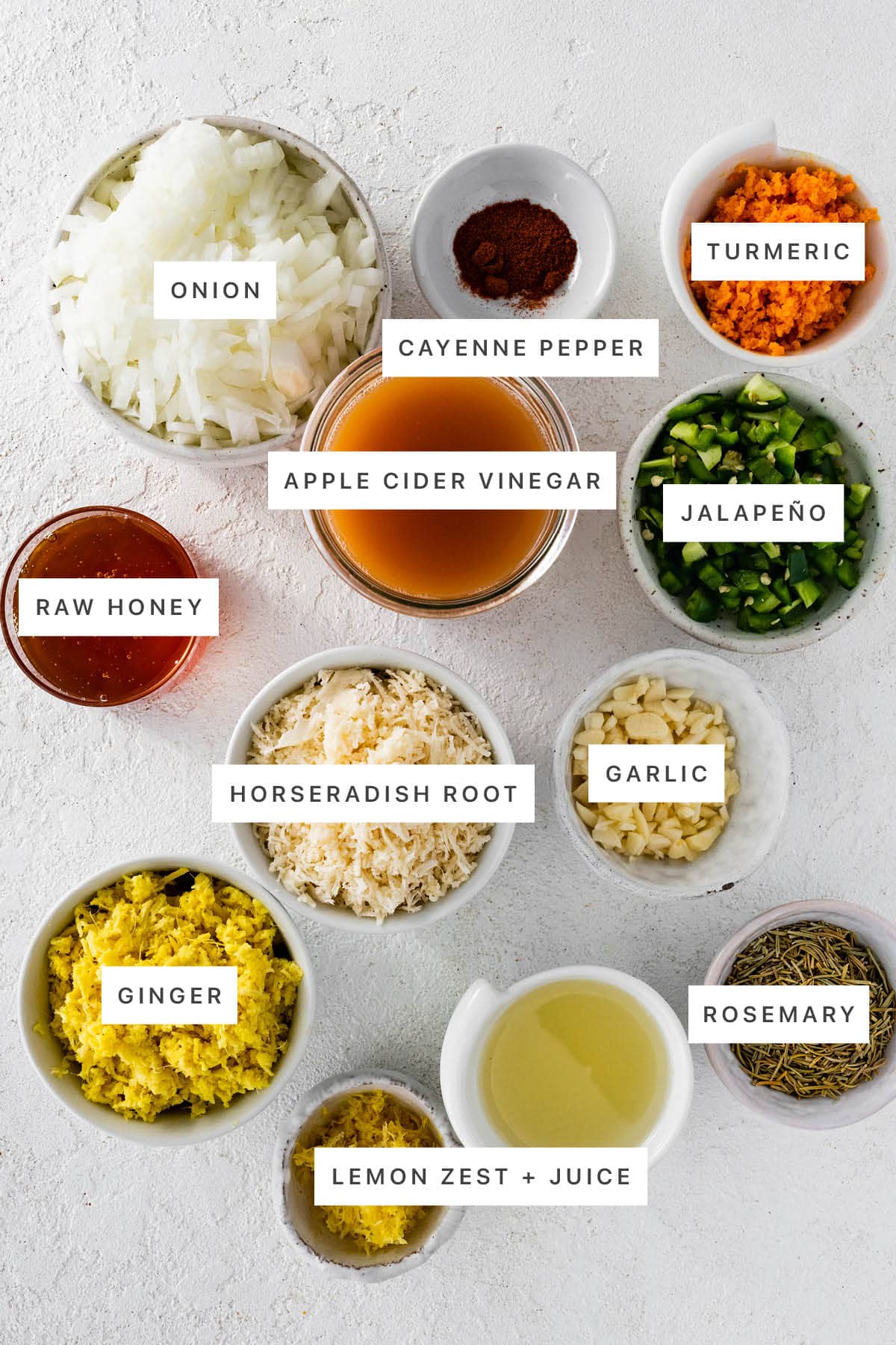 Ingredients measured out to make Fire Cider: onion, cayenne pepper, turmeric, apple cider vinegar, jalapeño, raw honey, horseradish root, garlic, ginger, lemon zest, lemon juice and rosemary.