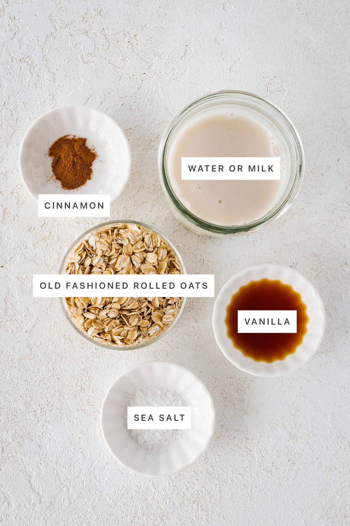 Ingredients measured out to make oatmeal: cinnamon, milk, oats, vanilla and sea salt.