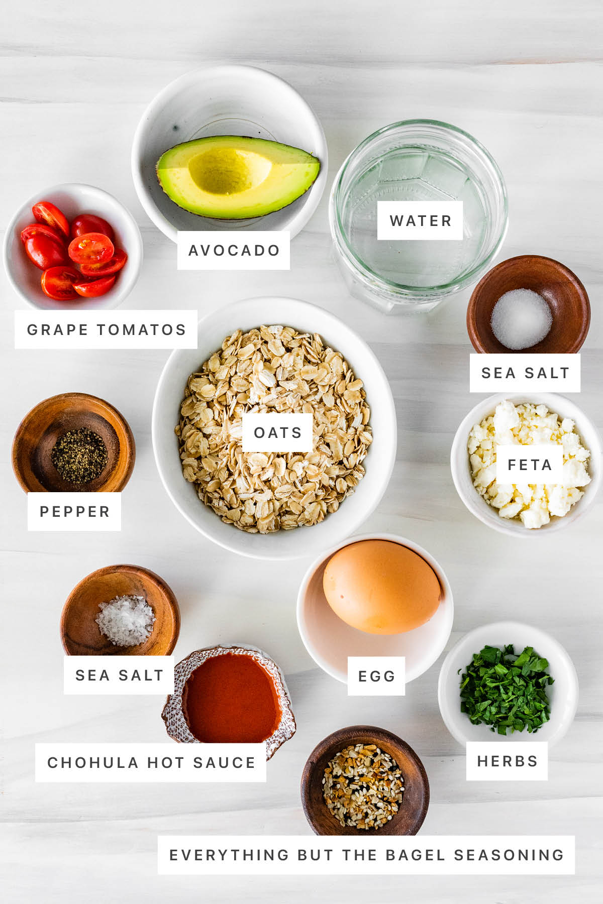 Ingredients measured out to make Savory Oatmeal: avocado, water, grape tomatoes, oats, sea salt, pepper, feta, egg, Chohula hot sauce, everything but the bagel seasoning and herbs.