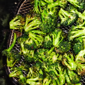 Seasoned air-fried broccoli in an air fryer basket.