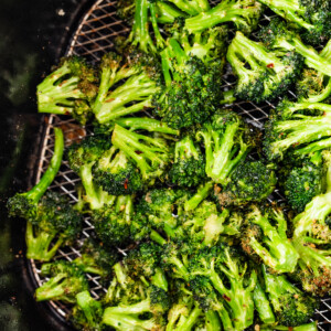 Seasoned air-fried broccoli in an air fryer basket.