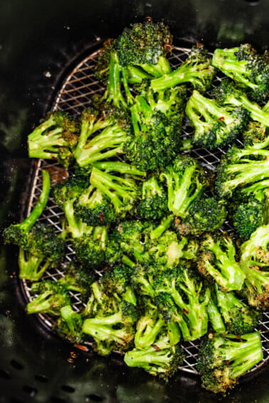 Seasoned air-fried broccoli in an air fryer basket.