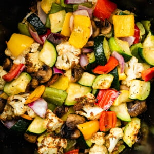 Air-fried vegetables in an air fryer. Vegetables include cauliflower, mushroom, onion, zucchini, and bell peppers.