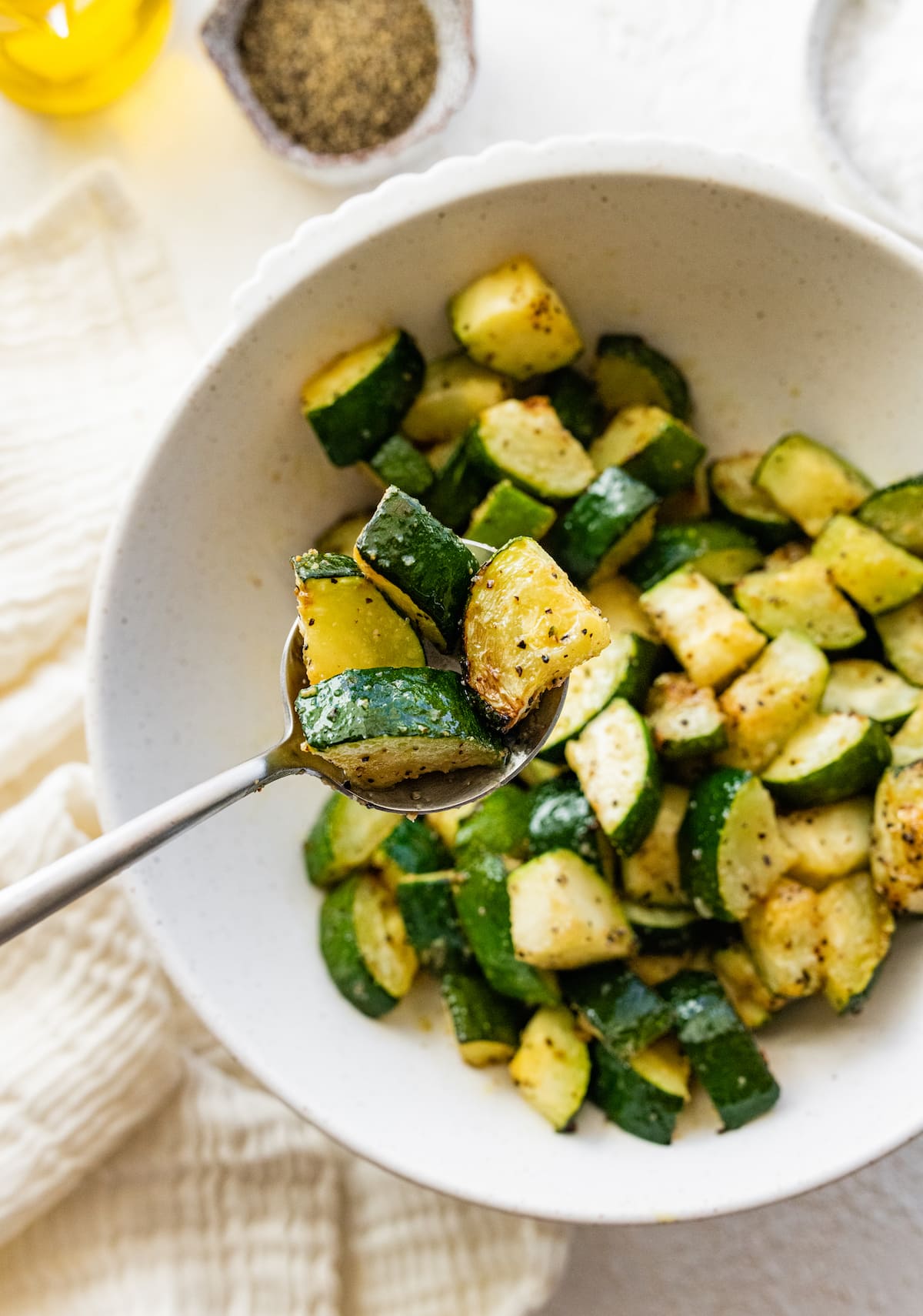 Air-fried zucchini in a bowl with a metal spoon.