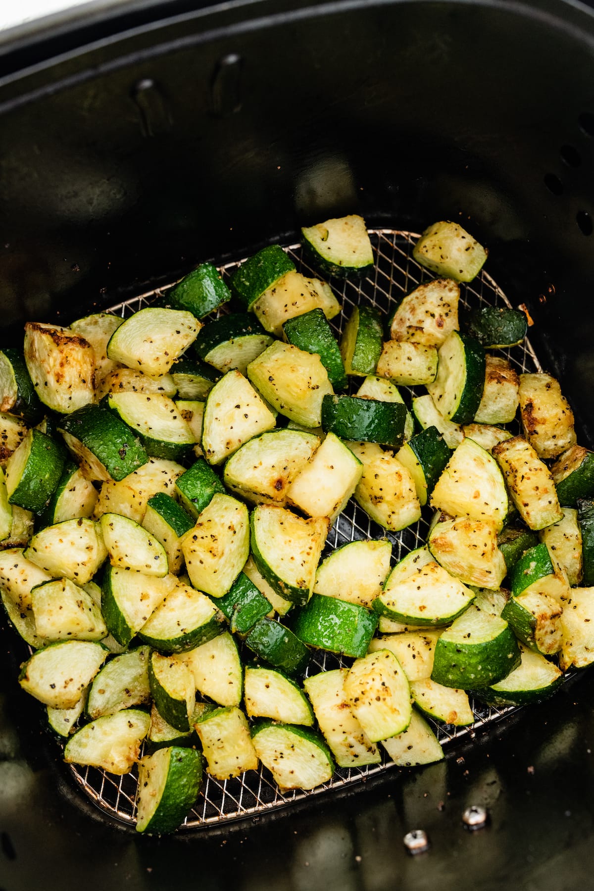 Air-fried zucchini in an air fryer basket.