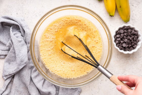 A woman's hand uses a whisk for the eggs used in an almond flour banana bread.