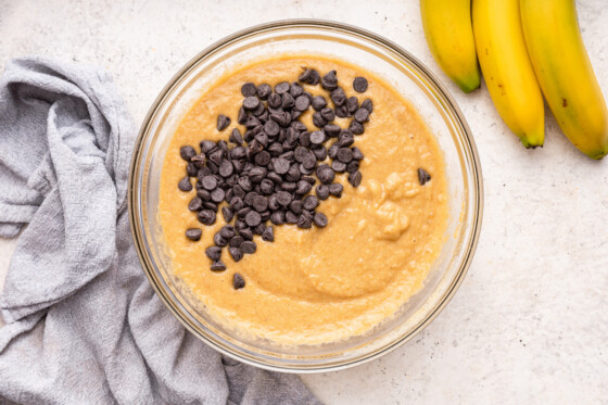 The dough used for almond flour banana bread in a large glass bowl, with chocolate chips added to it.