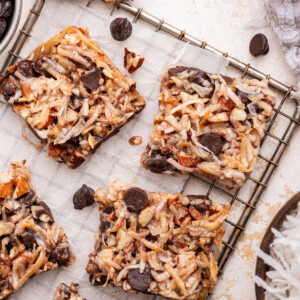 Multiple chocolate coconut bars on a metal cooling rack.