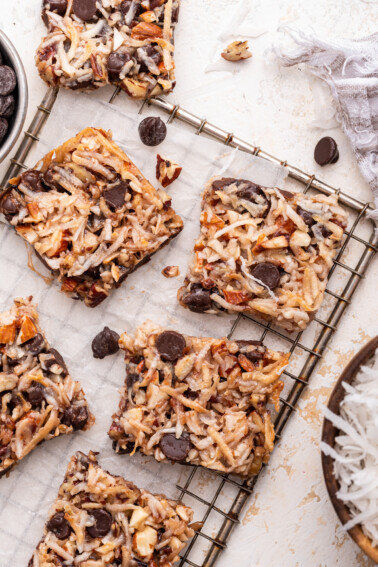 Multiple chocolate coconut bars on a metal cooling rack.