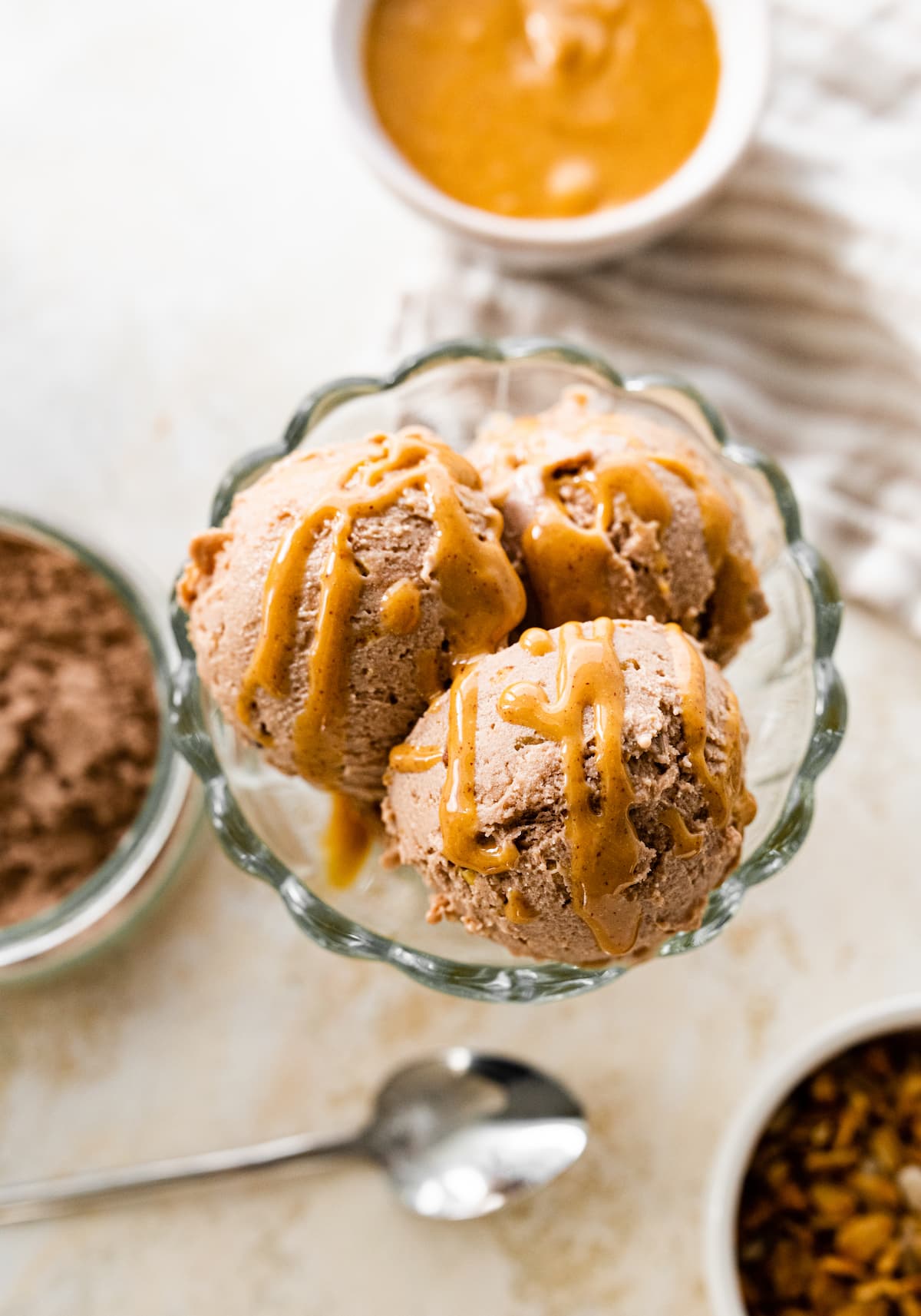 Chocolate peanut butter protein icee cream scooped in an ice cream bowl drizzled with peanut butter.