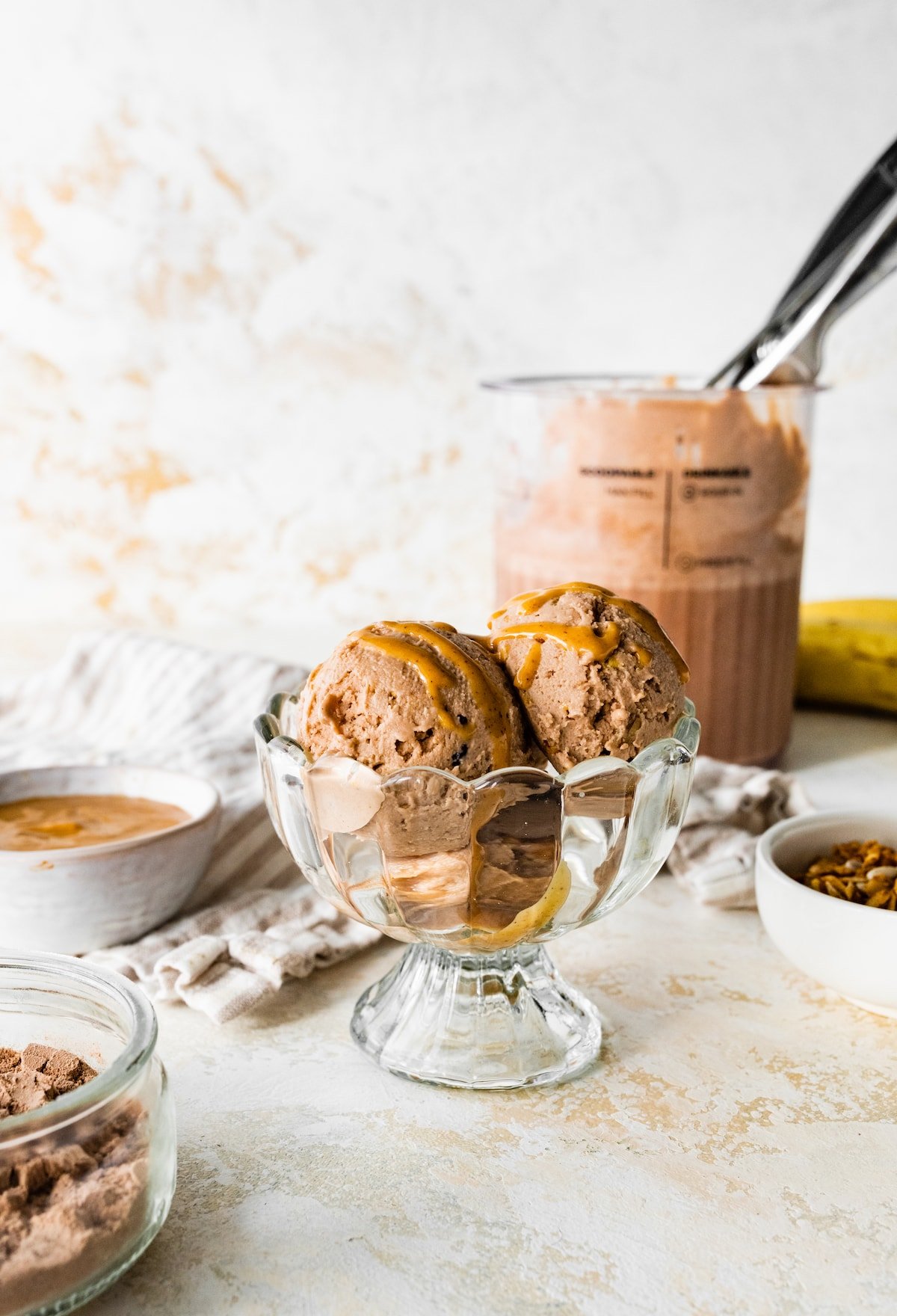 Chocolate peanut butter protein icee cream scooped in an ice cream bowl drizzled with peanut butter.