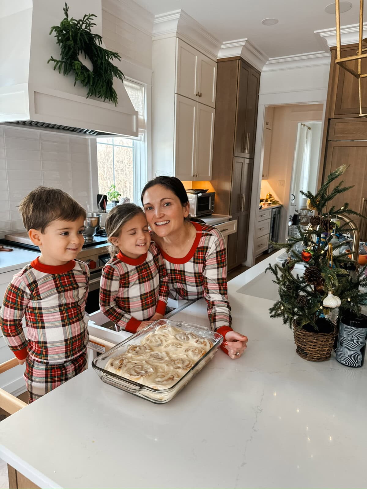 Woman with two kids with cinnamon rolls on Christmas morning. 
