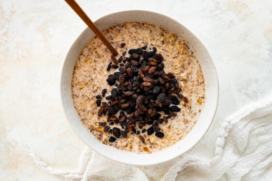 Raisins added to a large mixing bowl with the other ingredients to make the cinnamon raisin baked oatmeal.