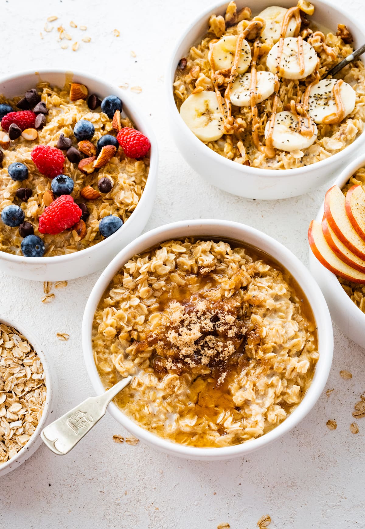 Four bowls of different oatmeal flavor variations: banana nut, apple cinnamon, maple brown sugar and berry almond.