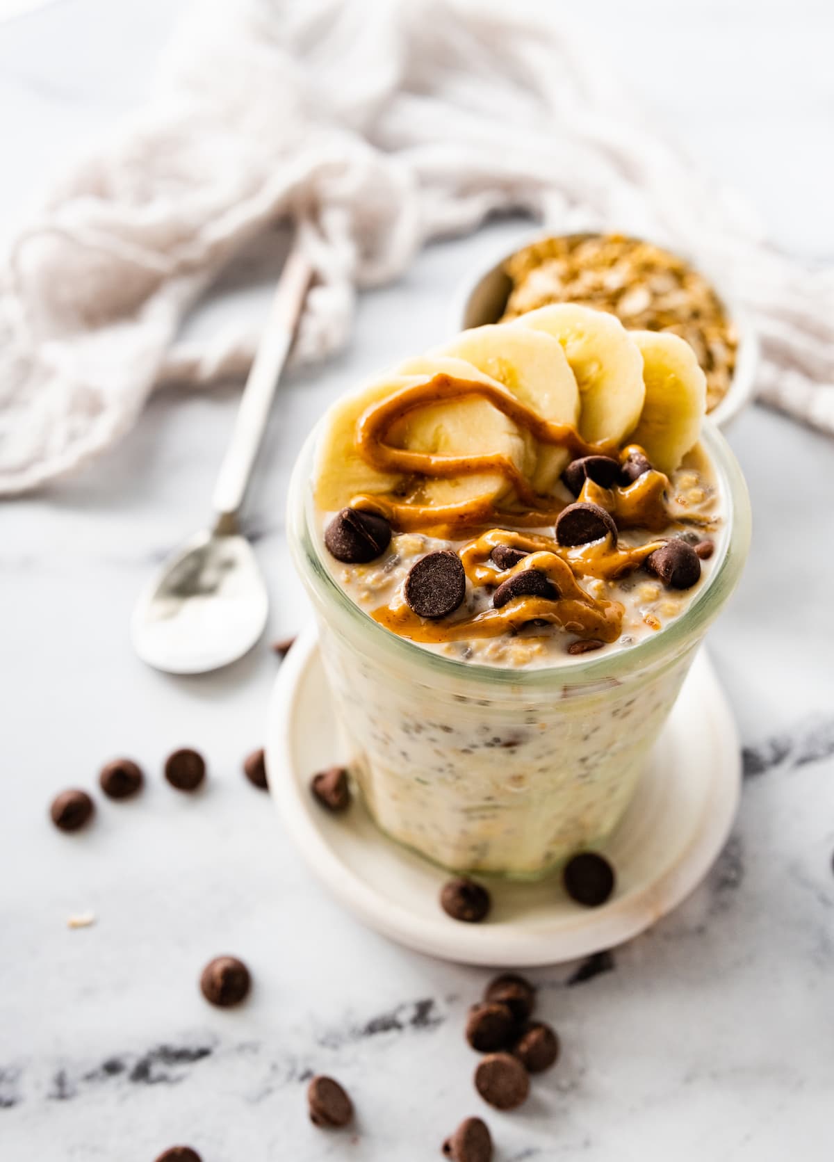 Overnight oats in a glass jar topped with fresh berries, nut butter, and nuts.