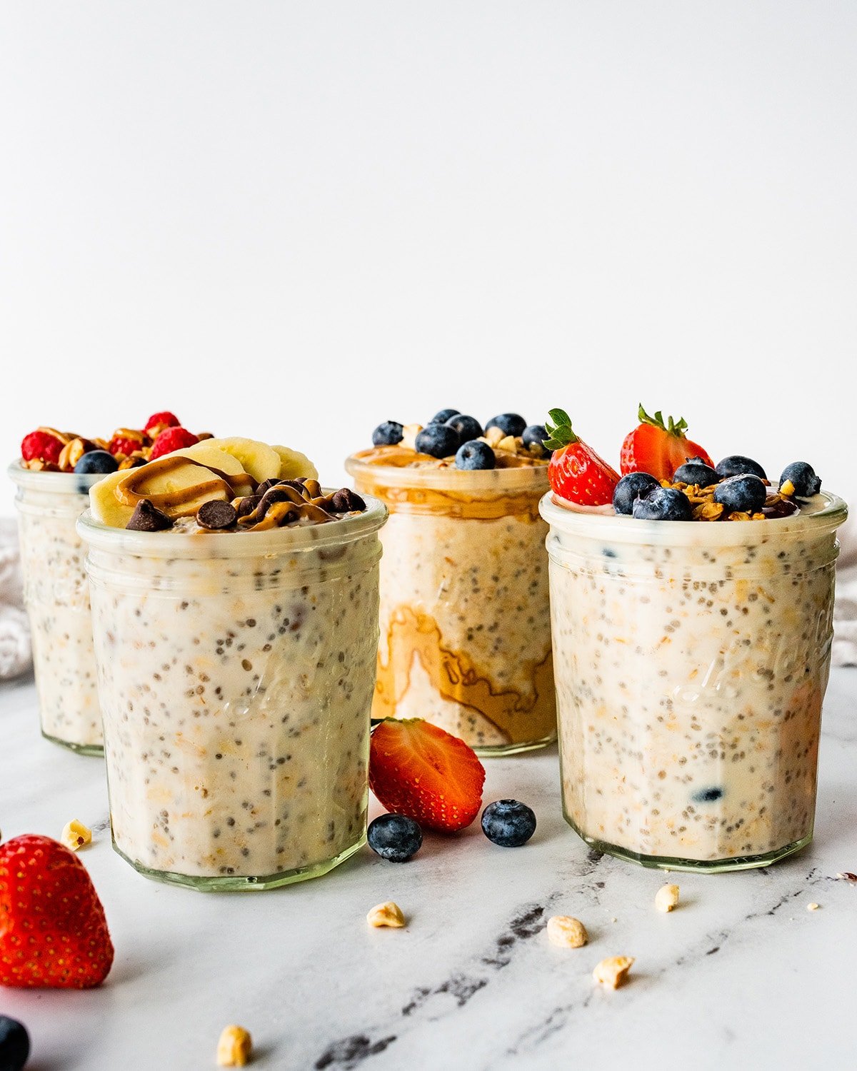 Four glass jars of overnight oats topped with fresh berries.