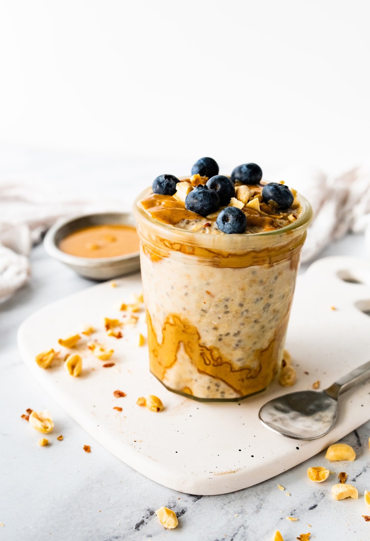A glass jar with overnight oats that are topped with fresh blueberries.