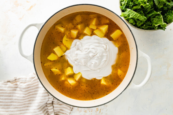 Heavy cream added to the zuppa toscana soup in a large pot.