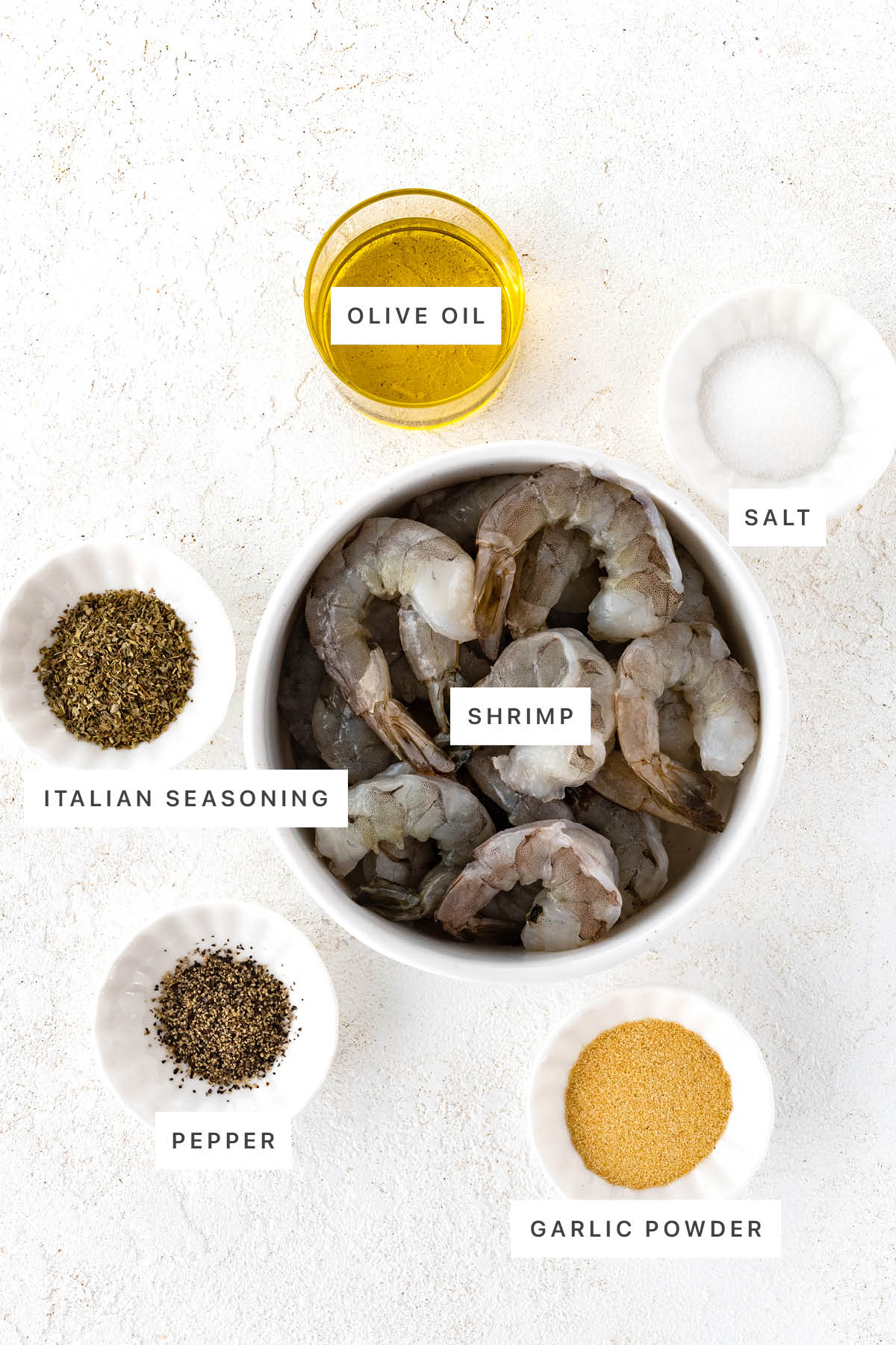 Ingredients measured out to make Air Fryer Shrimp: olive oil, salt, Italian seasoning, shrimp, pepper and garlic powder.