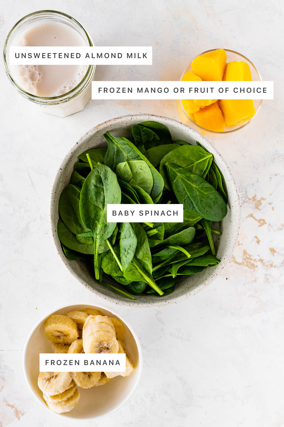 Ingredients measured out to make a Green Smoothie: almond milk, frozen mango, spinach and frozen banana.