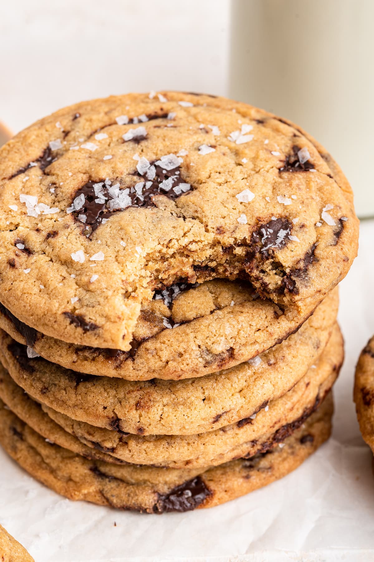 Brown butter chocolate chip cookies stacked on one another with the top cookie having a small bite taken from it.