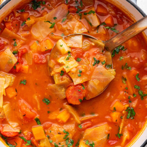 A large pot of cabbage soup with a ladle.