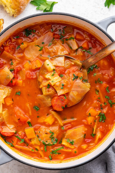 A large pot of cabbage soup with a ladle.