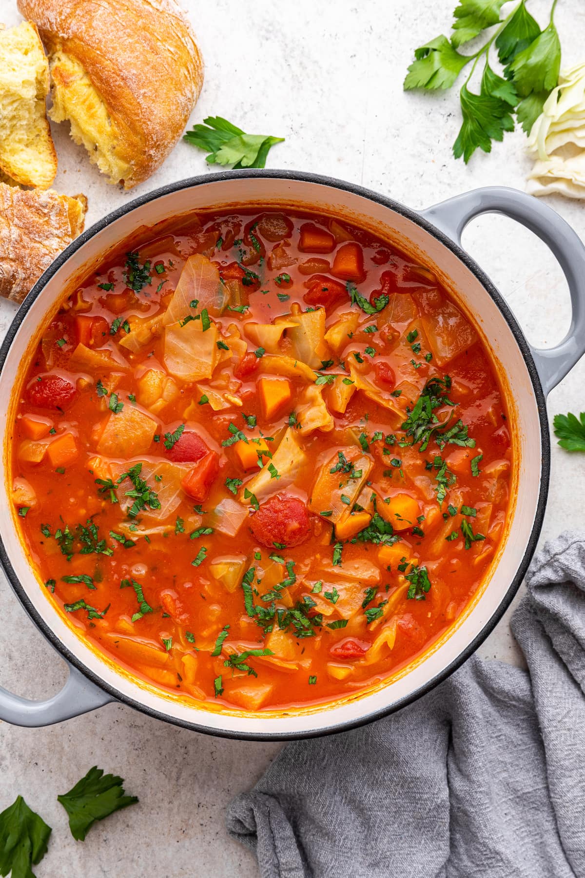 A large pot of cabbage soup with fresh herbs.