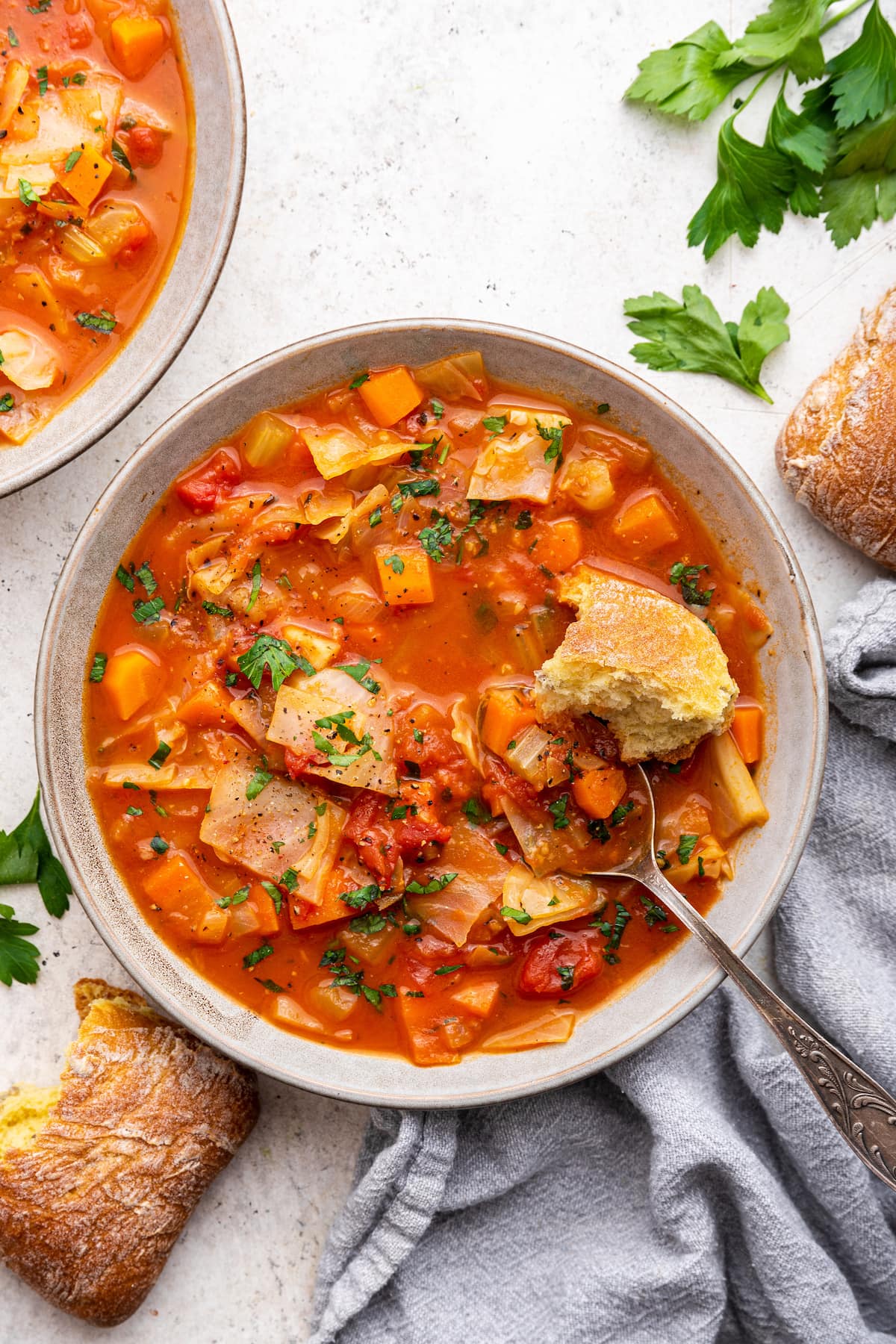 Cabbage soup in a bowl with a piece of bread inside the soup.